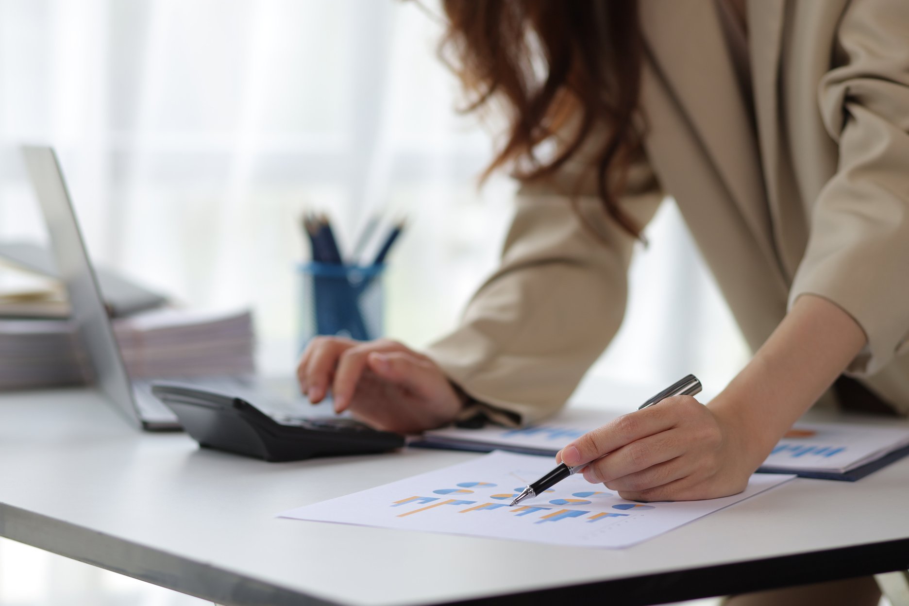 Businesswoman or accountant working with financial documents is analyzing and calculating with a calculator.